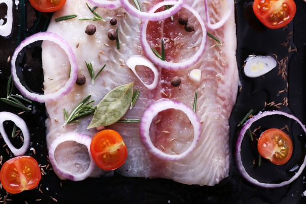 Выложить рыбу вместе с овощами и розмарином на противень.
