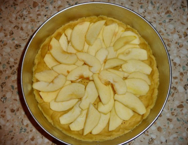 На охлажденном тесте разложить два крупных, нарезанных тонкими дольками яблока и поставить в духовку при 200 С на 20-25 минут.